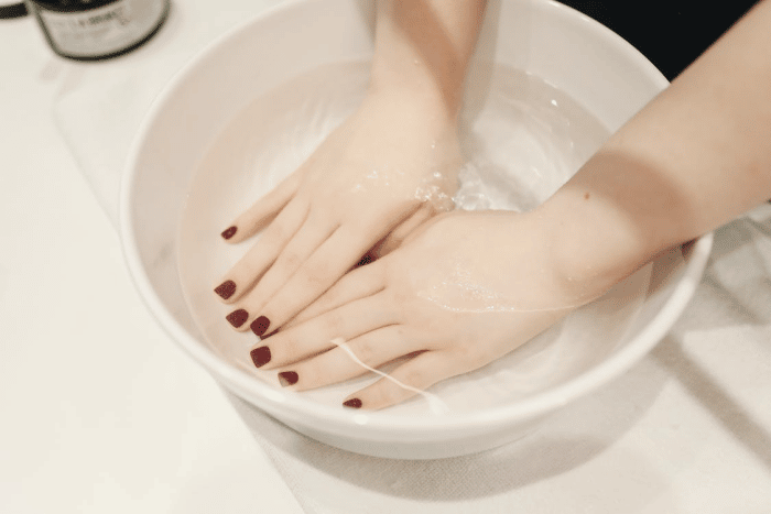 Woman Soaking Both Hands with Press On Nails in Warm Water