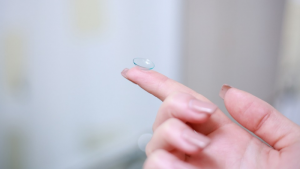 A Single Contact Lens Resting on a Finger with a Long Nail
