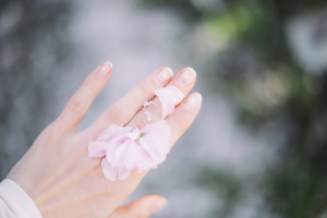 A Hand with Flower Petals on it, Featuring Neatly Trimmed Nails with Fingernail Nail Embellished with a Stone